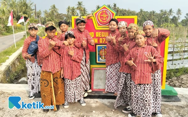 Foto Anak-anak foto didepan tugu prasasti tanda telah dilaksanakannya TMMD Reguler ke-124 Kodim 0732/Sleman yang terletak di persimpangan jalan antara Ngentak dan Glagahombo Pondokrejo Kapanewon Tempel Sleman. (Foto: Pendim 0732/Sleman for Ketik.co.id)