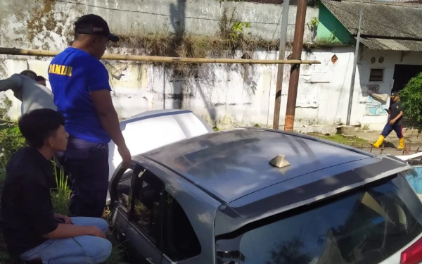 Gambar Mobil Angkutan Online Terperosok di Selokan Jalan Sempit, Damkar Jember Bantu Evakuasi