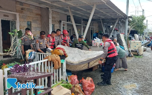 Foto Personel kepolisian membantu mengangkat kasur warga yang basah terkena banjir. (Foto: Husni Habib/ Ketik.co.id)